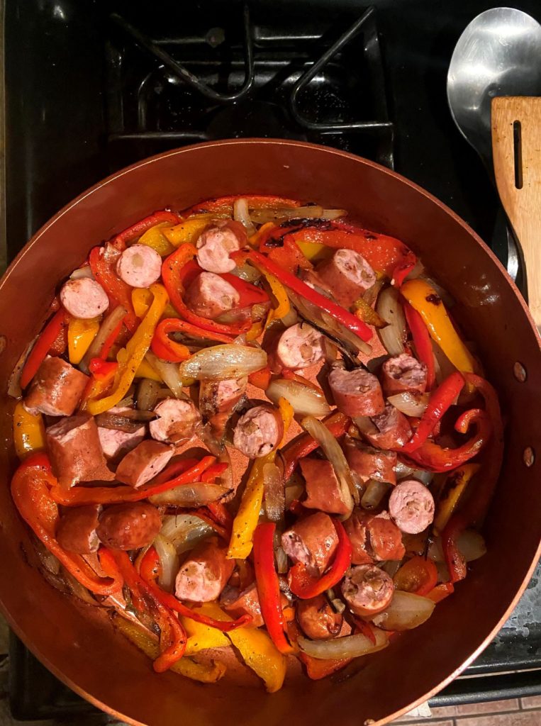 Cooked chicken sausage, peppers, and onions in a pan on the stovetop