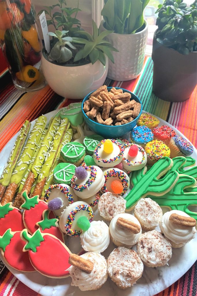 Tray of cactus cookies, margarita glass cookies, mini churros, and cupcakes