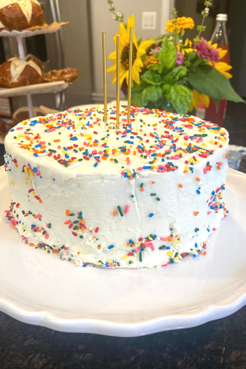 Brownie birthday cake frosted with vanilla buttercream icing, topped with rainbow sprinkles