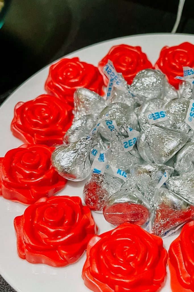 Small red chocolates that look like a rose on a plate with hershey kisses